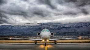 Avião privado na pista, com nuvens ao fundo
