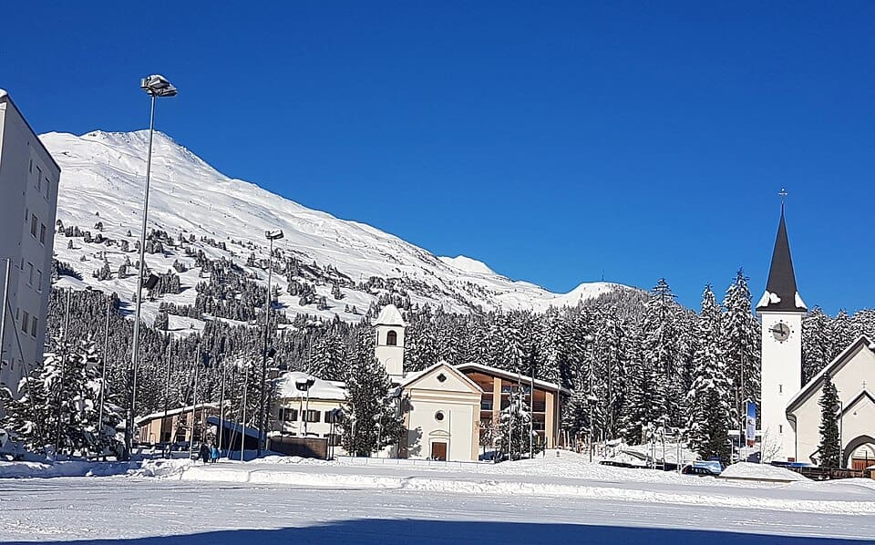 View of the Voa Sporz street and San Carlo church in Lenzerheide village during winter